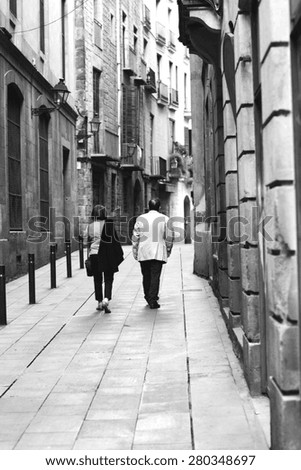 An older couple walking in the narrow streets. Image in black and white.