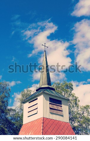 Old church tower with a cross against a deep blue sky in the summer. Image has a vintage effect.