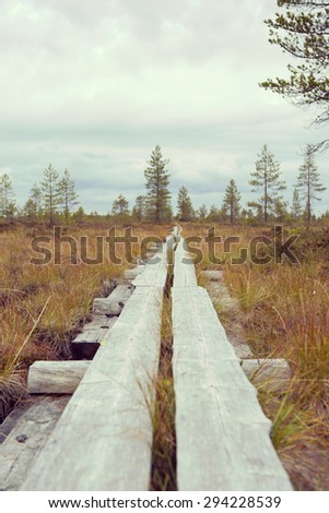 Nature trail made from duckboards in the northern part of Finland during autumn. Image has a vintage effect.