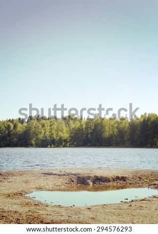 A beach made of rock in Finland. Image of a lake view from the cliff. Image has a vintage effect.
