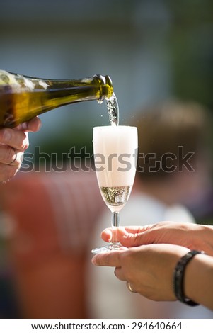 Pouring champagne for a celebration in the summer time outdoor.