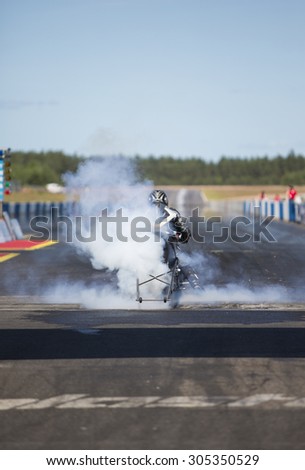 A motorcycle driver is doing burnout in the start line of a drag race strip.