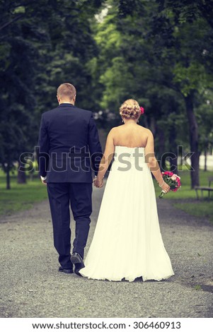 Just married. A lovely shot of just married couple walking towards the future together. Woman has a beautiful wedding dress and man a black suit. Image has a vintage effect applied.