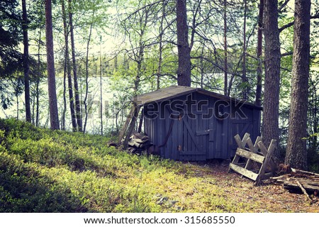 An image of an An old shed which is built for storing wood and tools in the countryside of Finland. Image has a vintage effect applied.