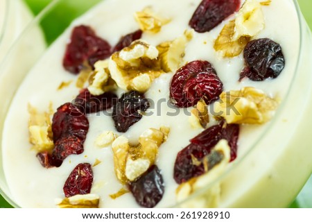 Banana smoothie with crushed walnuts and dried cherries on top