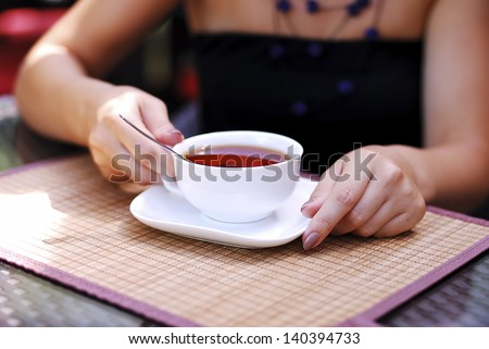 Hands holding a cup of tea Woman holding a cup of black tea