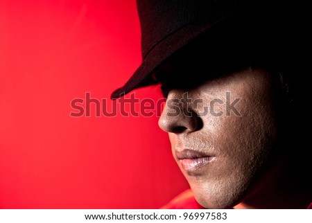 Handsome man portrait with hat dark eyes mistery and beauty concept on red background