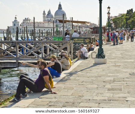 VENICE, ITALY - JUNE 6: tourists relaxing by the water on June 6, 2013 in Venice, Italy. Venice is one of the world\'s most popular tourist destinations with 21 million visitors per annum.