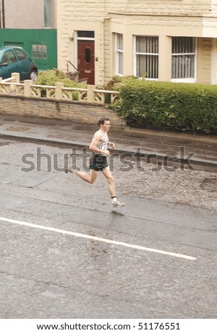 EDINBURGH - APRIL 18: A runner leads the Edinburgh Chris Hoy Half Marathon, here going down Lochend Road, on April 18th, 2010 in Edinburgh, UK.