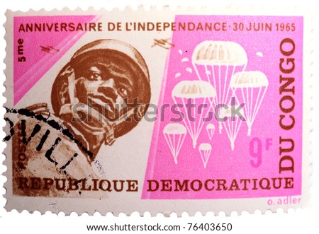 DEMOCRATIC REPUBLIC OF CONGO - CIRCA 1965: a bright pink and brown, 9fr, stamp from the Democratic Republic of Congo shows image of a Congolese paratrooper and parachutes, circa 1965