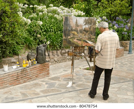 MALAGA, SPAIN - JUNE 25: a man paints on canvas on June 25, 2011 in Malaga, Spain. Birthplace of Picasso, Malaga is a city in which it is common to find artists painting in the streets and parks.