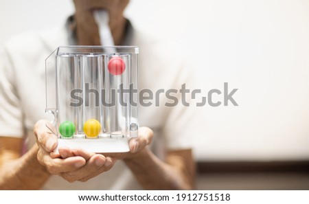 The old patient hand holding the Tri-ball incentive spirometry is medical equipment for post operation. The equipment for Lungs function testing and Pulmonary test.