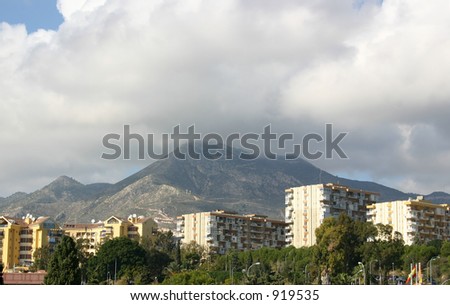 mountain at the back of the city with low clouds above