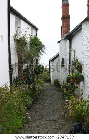 old cottaages with narrow cobble path between them decorated with flowers and shrubs