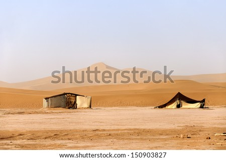 Hamada du Draa (Morocco stone desert)  sand dunes with tents in foreground