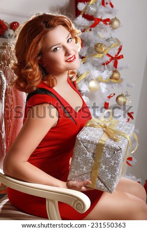 Christmas and New Year. Woman with a gift box in the beautiful interior with a Xmas tree