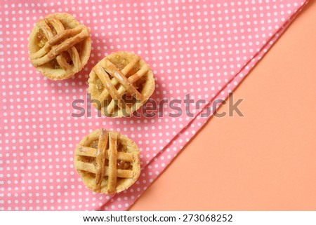 Pineapple pies on pink and white polka dot background. View from top, closed up.