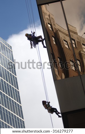 VANCOUVER, CANADA - SEPTEMBER 10, 2014: A man climbs down office building during Easter Seals Drop Zone fundraiser to benefit children with disabilities in Vancouver, Canada, on September 10, 2014.