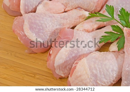 Fresh chicken legs on wooden chopping board
