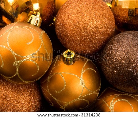 Gold Christmas baubles in a nest of black feathers over white background.