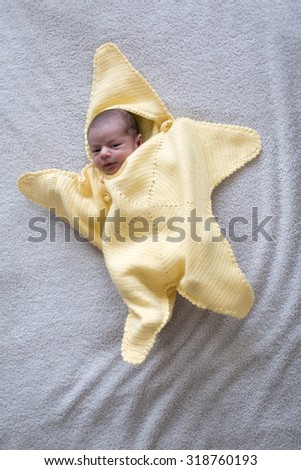 cute newborn baby boy smiling and with open eyes looking\
on a soft white blanket background\
the baby is awake and it\'s eyes and mouth are open