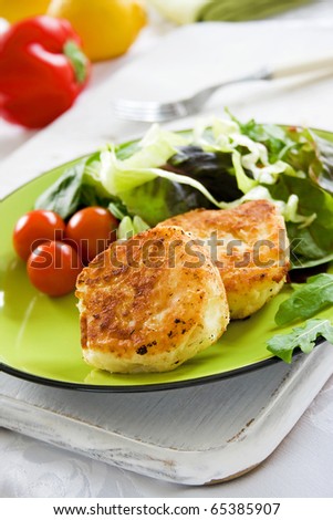 Two potato cakes on a plate with fresh green salad