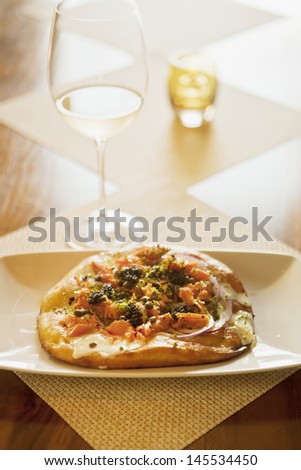 maple-smoked salmon pizza with lemon creme fraiche and a glass of sauvignon blanc wine