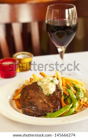 hearty flat iron steak with mashed potatoes, fries and vegetables with glass of pinot noir wine