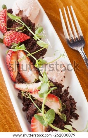 creative dessert made with crumbled chocolate cake, strawberry gelato and organic strawberries topped with a sweet-pea sprig