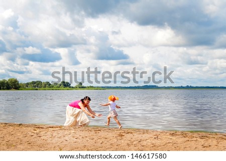 child runs to his mother on the banks of the river