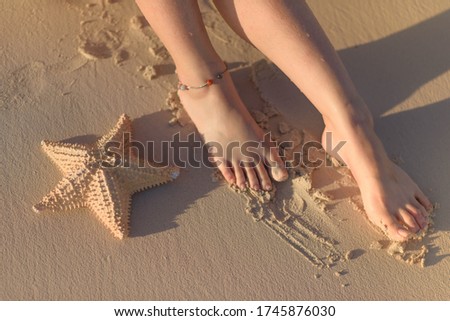 Women's feet and starfish on yellow sand. Stock fotó © 