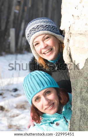 Two girl looks out from round the corner