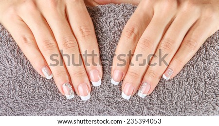 Female soft hands with beautiful french manicure on the towel