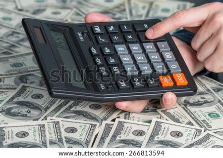 Man\'s hands with money and calculator. Money saving concept.