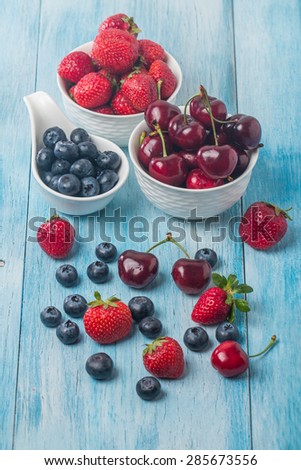 Berries mix in bowl on blue wooden background