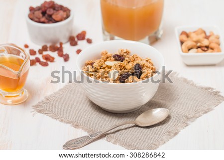 Granola, honey, nuts and raisins on white wooden background. Fitness breakfast.