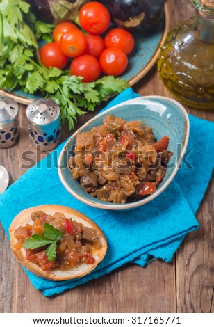 Eggplant caviar in a bowl on wooden background closeup