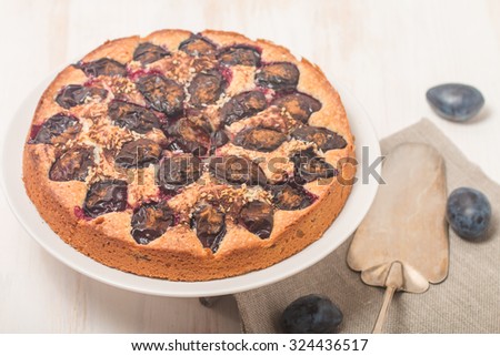 Plum cake with fresh plums on white wooden table