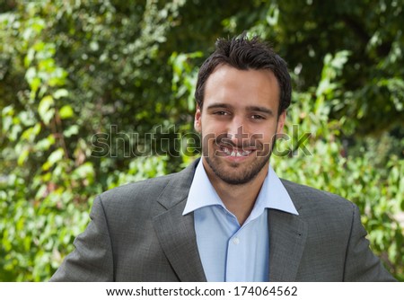 Attractive latin businessman in a park looking at camera