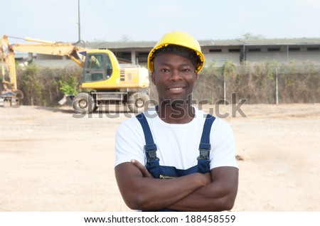 Laughing african worker with crossed arms at construction site