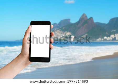 Hand holding mobile phone with blank screen at Ipanema beach at Rio de Janeiro at Brazil Foto stock © 