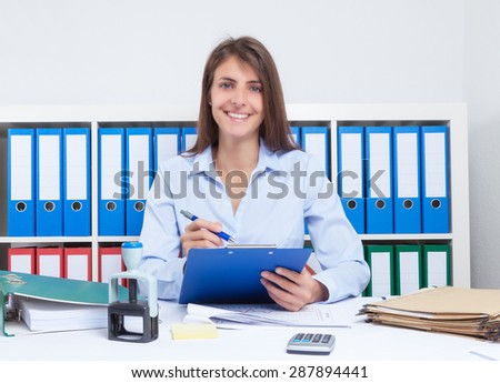 Happy secretary with long brown hair at work at office