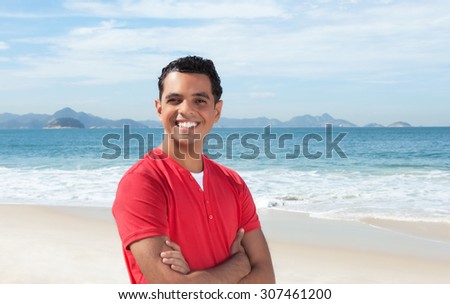 Laughing latin guy with crossed arms at beach
