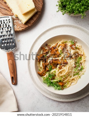 Italian cuisine. Pasta with chanterelles and parmesan cheese. Spaghetti with mushrooms and micro-greens. Pasta with cheese and vegetables. Italian dinner. Italian food on a gray background.