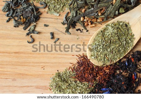 Dry mate tea in a spoon on wooden background with tea collection