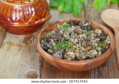 Pearl barley with mushrooms on wooden rustic table