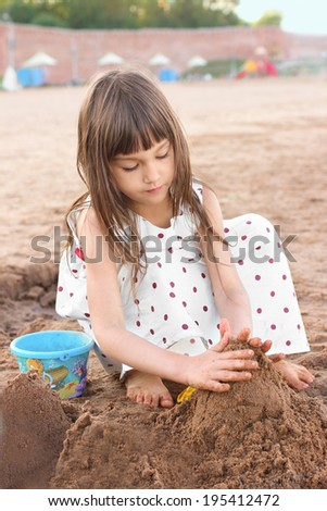 Cute little girl making sand castle on river beach. Femininity concept