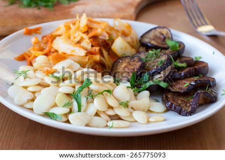 Healthy vegan food. Roasted eggplants, white beans and cooked cabbage