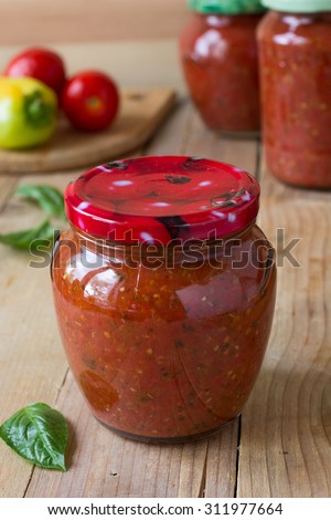 Homemade preserved tomato sauce with bell pepper, basil and oregano in a glass jar