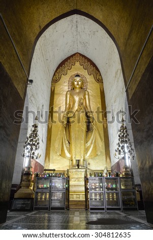 BAGAN, MYANMAR - JULY 30: Standing Buddha Kassapa at  the Ananda temple adorned by believers by sticking golden leaves on statue on July 30, 2015 in Bagan, Myanmar.